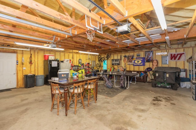 garage with electric panel, a garage door opener, and freestanding refrigerator