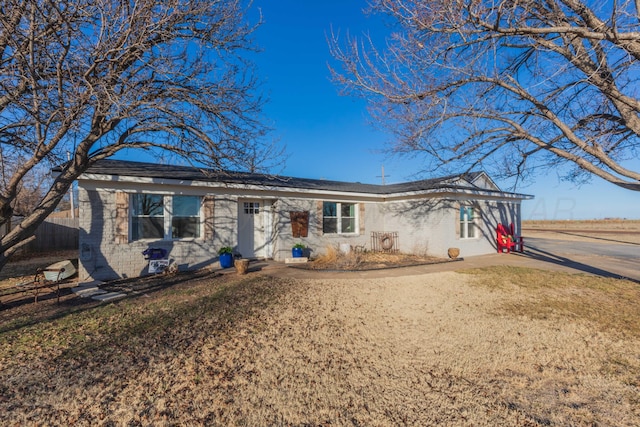 single story home featuring a front lawn, fence, and brick siding