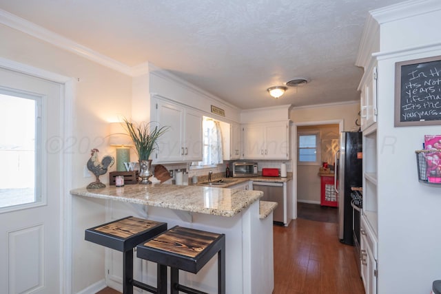 kitchen featuring visible vents, appliances with stainless steel finishes, a peninsula, crown molding, and white cabinetry