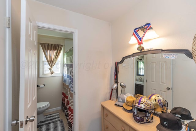 bathroom featuring toilet, baseboards, and a shower with shower curtain