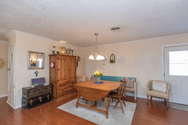 dining room featuring a chandelier, ornamental molding, wood finished floors, and visible vents