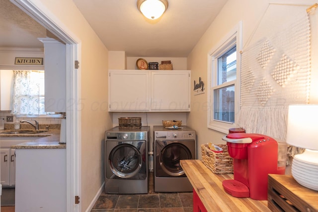 washroom featuring cabinet space, baseboards, separate washer and dryer, and a sink