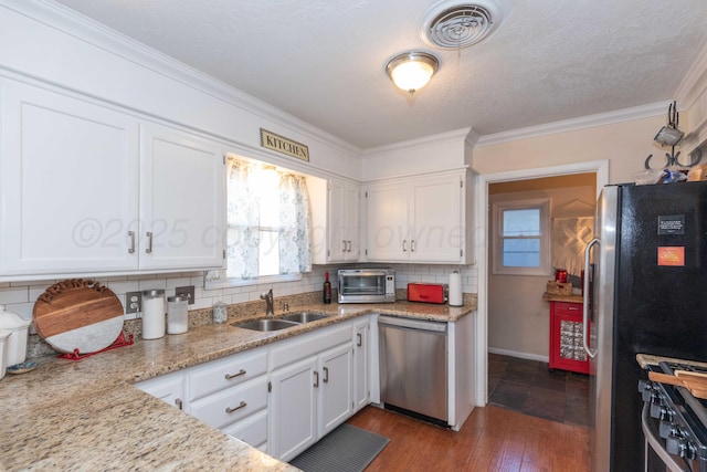 kitchen with appliances with stainless steel finishes, a sink, visible vents, and white cabinets