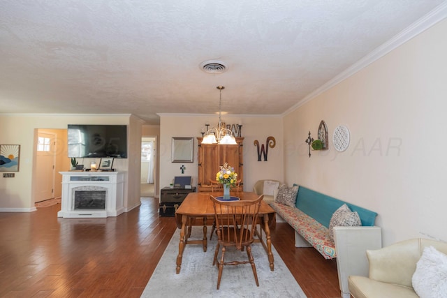 dining space featuring wood finished floors, visible vents, crown molding, and an inviting chandelier