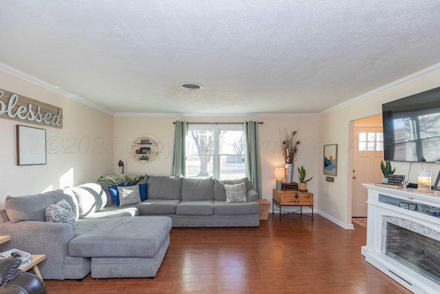 living room featuring dark wood-style floors, visible vents, crown molding, and a fireplace