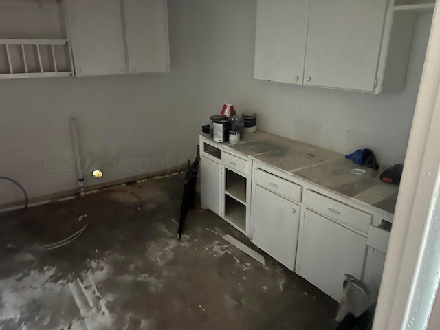 104 Peiffer St, Borger, TX 79007 - kitchen with open shelves, light countertops, white cabinetry, and unfinished concrete floors