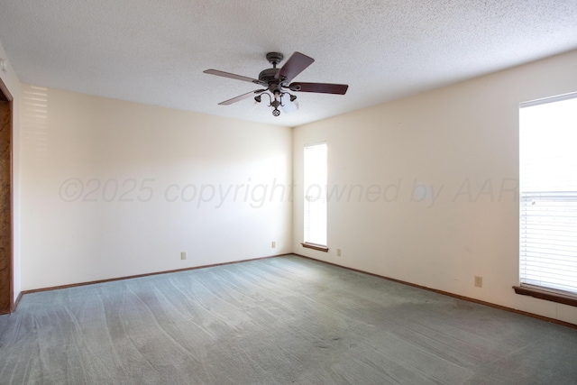 carpeted empty room featuring baseboards, a ceiling fan, and a textured ceiling