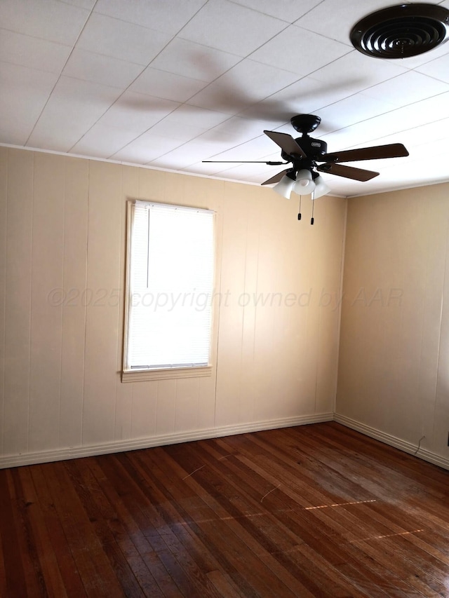 spare room featuring a ceiling fan, visible vents, dark wood finished floors, and baseboards