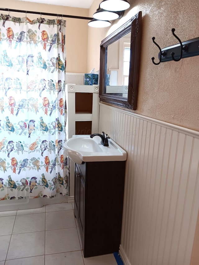 bathroom featuring wainscoting, a textured wall, vanity, and tile patterned floors