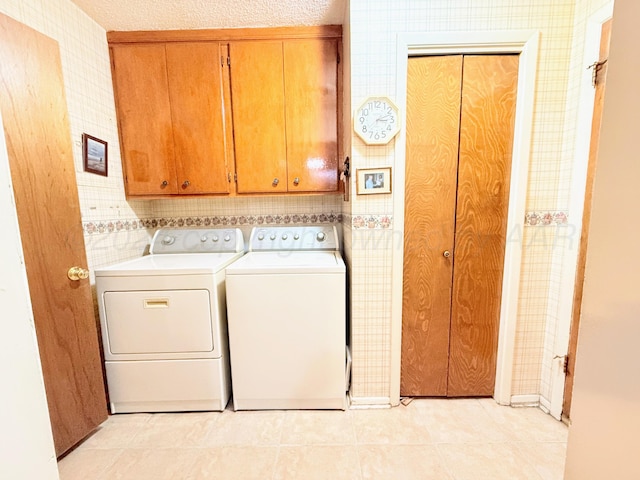 washroom featuring cabinets, separate washer and dryer, a textured ceiling, and light tile patterned floors