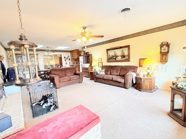 carpeted living room featuring ceiling fan, ornamental molding, and a skylight