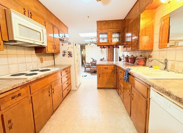 kitchen featuring a skylight, sink, a textured ceiling, white appliances, and decorative backsplash