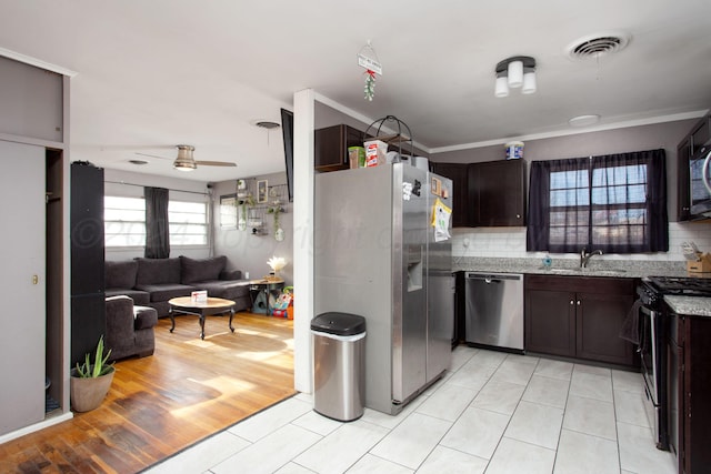 kitchen featuring appliances with stainless steel finishes, backsplash, light hardwood / wood-style flooring, and ceiling fan