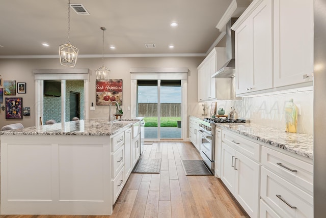 5504 Wesley Dr, Amarillo, TX 79119 - kitchen featuring stainless steel stove, an island with sink, light wood-type flooring, white cabinets, and ornamental molding