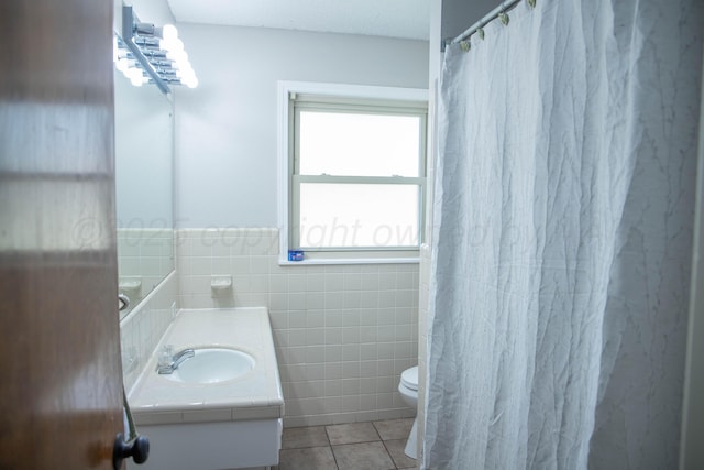 301 Maple Ave, Panhandle, TX 79068 - bathroom featuring tile patterned floors, tile walls, vanity, and a wainscoted wall