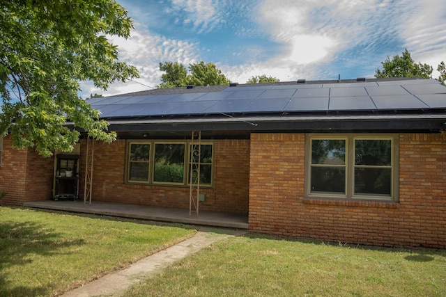301 Maple Ave, Panhandle, TX 79068 - rear view of house featuring brick siding, a lawn, and roof mounted solar panels