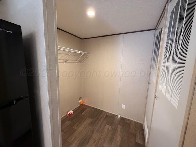 clothes washing area featuring a heating unit, dark wood-type flooring, and crown molding