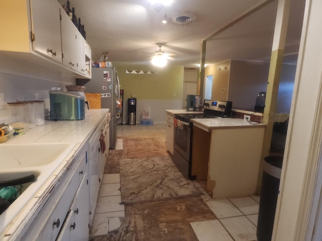 2706 Magnolia St, Amarillo, TX 79107 - kitchen with stainless steel appliances, white cabinetry, a ceiling fan, and tile countertops