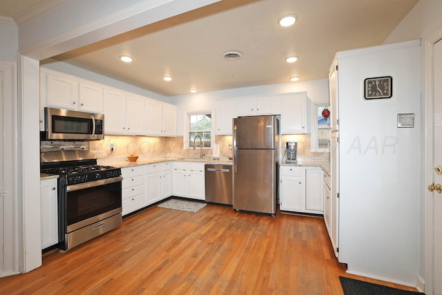 kitchen with white cabinets, light wood-type flooring, appliances with stainless steel finishes, decorative backsplash, and recessed lighting