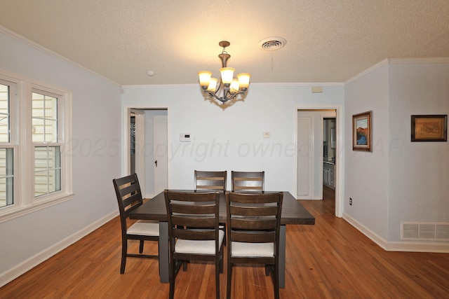 dining area featuring baseboards, an inviting chandelier, visible vents, and wood finished floors