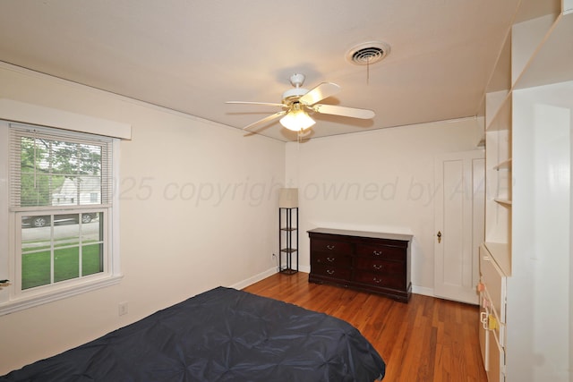 bedroom with baseboards, ceiling fan, visible vents, and wood finished floors