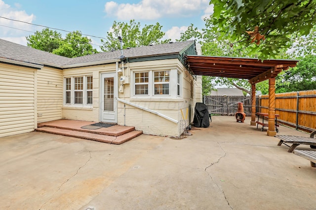 back of house with a fenced backyard, a patio, a shingled roof, and a carport