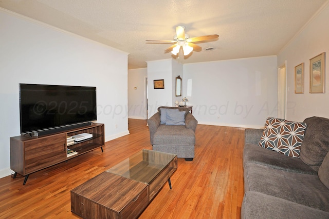 living area featuring light wood-type flooring, baseboards, a ceiling fan, and ornamental molding