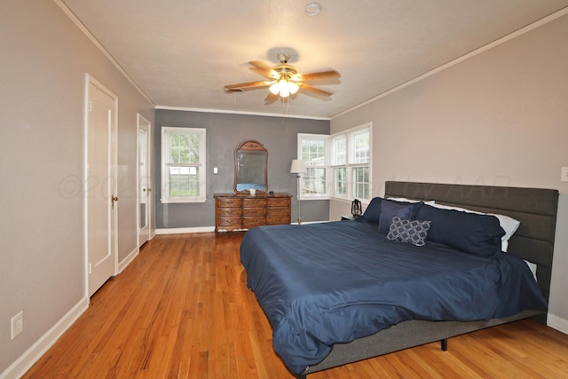 bedroom with baseboards, crown molding, a ceiling fan, and wood finished floors