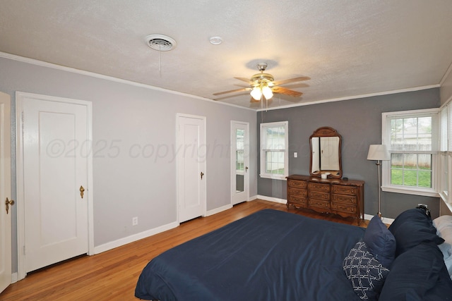 bedroom featuring crown molding, baseboards, visible vents, and wood finished floors