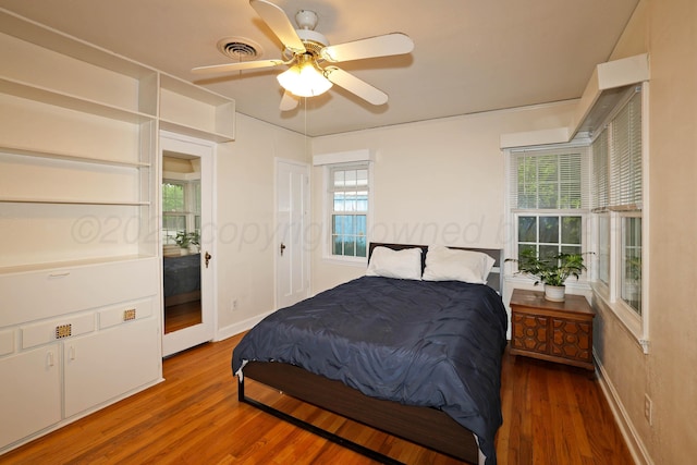 bedroom featuring wood finished floors, baseboards, and multiple windows