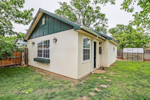 view of property exterior featuring a yard, fence, an outbuilding, and an exterior structure