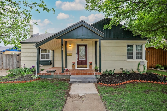bungalow-style house with covered porch, fence, a chimney, and a front yard