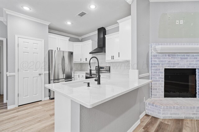 9317 Shylana Ave, Amarillo, TX 79119 - kitchen with wall chimney exhaust hood, appliances with stainless steel finishes, ornamental molding, light wood-style floors, and a peninsula