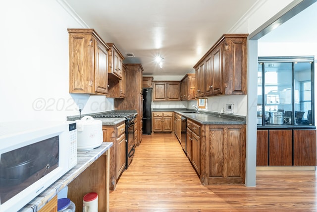 3519 S Julian Blvd, Amarillo, TX 79102 - kitchen with brown cabinets, a sink, light wood finished floors, visible vents, and black appliances