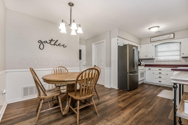 7703 Farrell Dr, Amarillo, TX 79121 - dining area with dark wood-style floors, a chandelier, a wainscoted wall, and a textured ceiling
