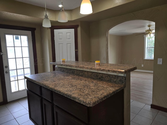 1313 Skyline Dr, Amarillo, TX 79108 - kitchen with a center island, light tile patterned flooring, arched walkways, and dark countertops