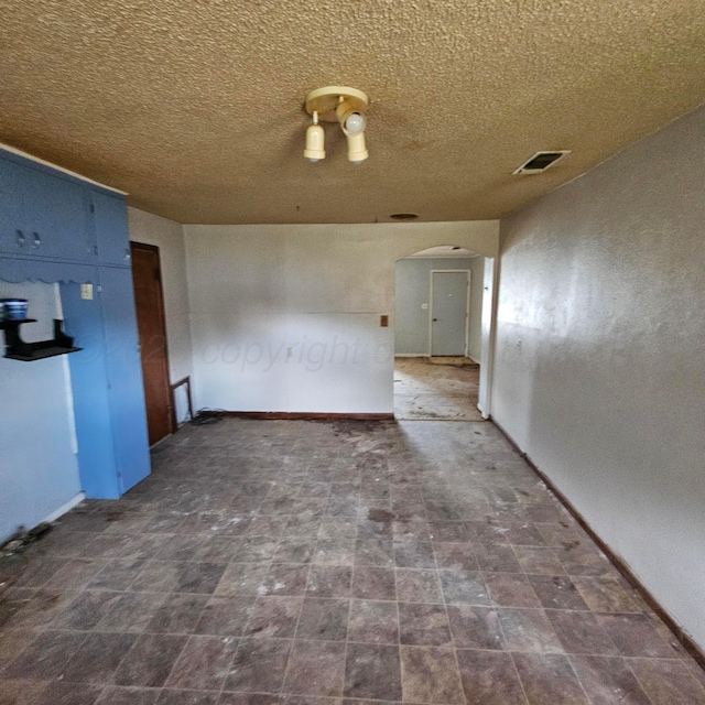 1206 Durrett Ave, Dumas, TX 79029 - spare room with arched walkways and a textured ceiling