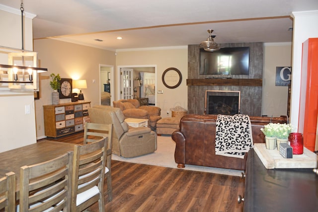 living room featuring dark wood-type flooring, ornamental molding, and a large fireplace