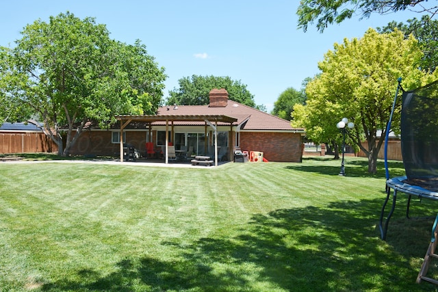 back of house with a patio, a yard, a pergola, and a trampoline