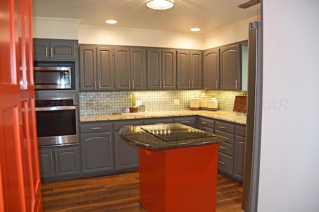 kitchen featuring stainless steel appliances, light stone counters, a center island, and dark hardwood / wood-style flooring