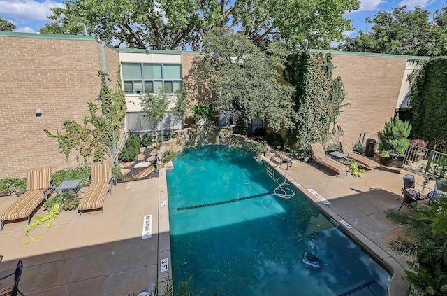 community pool with a patio area and fence