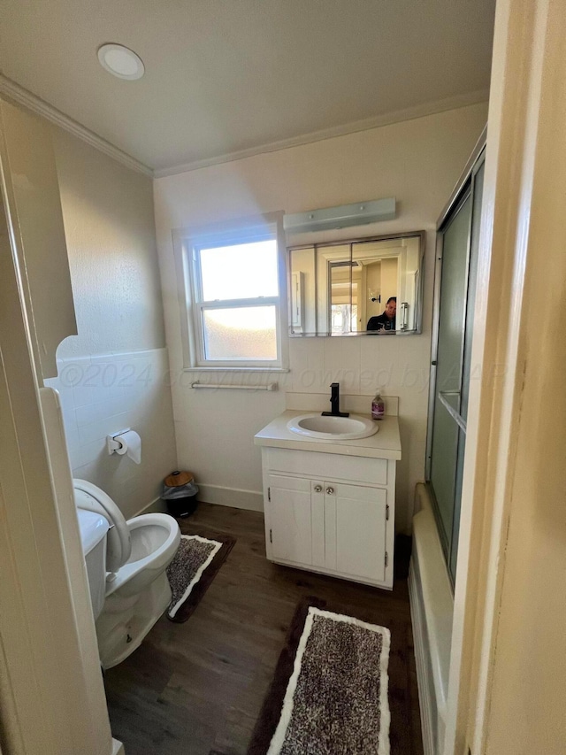 full bathroom featuring vanity, crown molding, wood-type flooring, enclosed tub / shower combo, and toilet