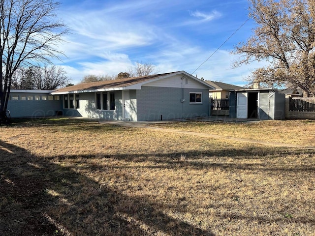 back of house with a yard and a storage unit