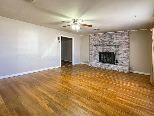 unfurnished living room featuring a brick fireplace, hardwood / wood-style flooring, and ceiling fan