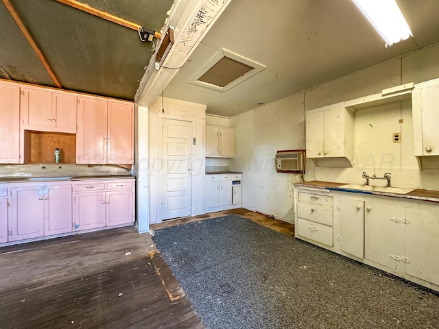 kitchen with white cabinetry, sink, dark hardwood / wood-style flooring, and a wall unit AC