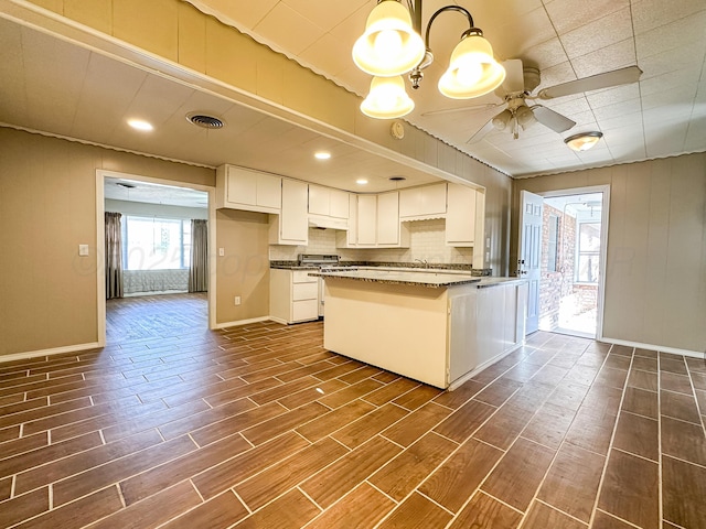 kitchen with sink, dark stone countertops, white cabinets, ceiling fan, and backsplash