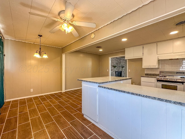 kitchen featuring gas stove, tasteful backsplash, hanging light fixtures, ceiling fan, and white cabinets