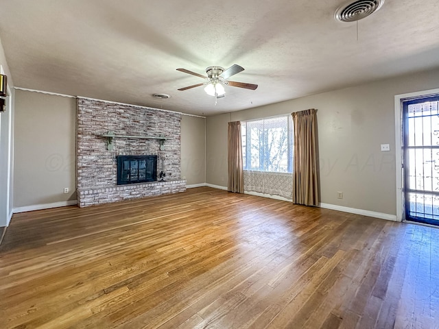 unfurnished living room with hardwood / wood-style flooring, ceiling fan, a wealth of natural light, and a fireplace