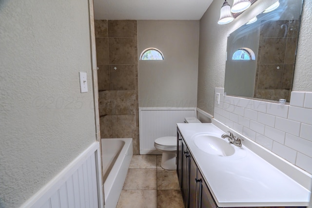 bathroom with healthy amount of natural light, a tub to relax in, vanity, toilet, and a textured wall