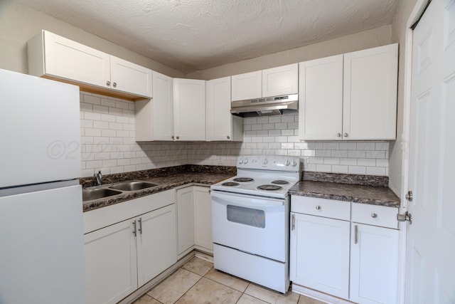 kitchen with white appliances, under cabinet range hood, a sink, dark countertops, and white cabinets